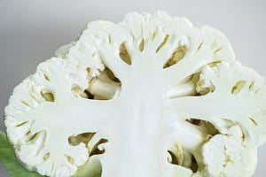 cauliflower cut in half to show stem, leaves, and florets