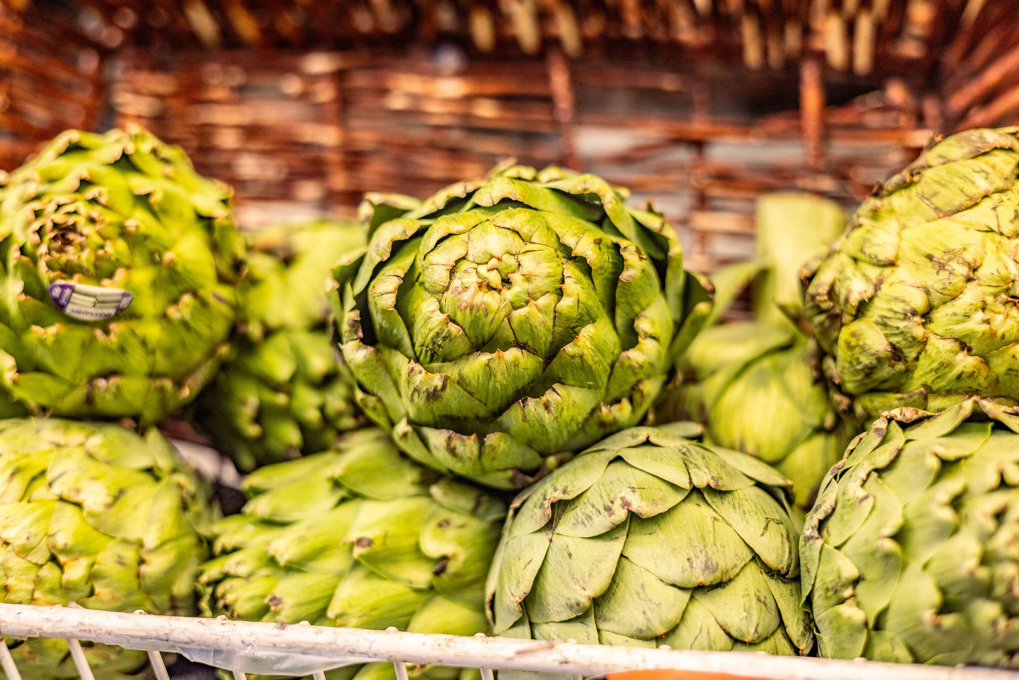 Eight artichokes are pictured, with the focus being on one artichoke in the center.